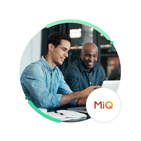 Uma foto de dois profissionais trocando ideias enquanto trabalham em um laptop com um logotipo da MiQ.